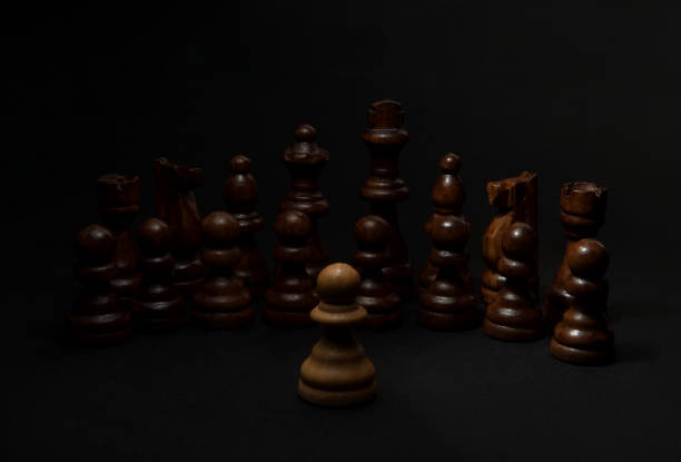 istock Chess. White pawn and Black figures on black background. 914920972