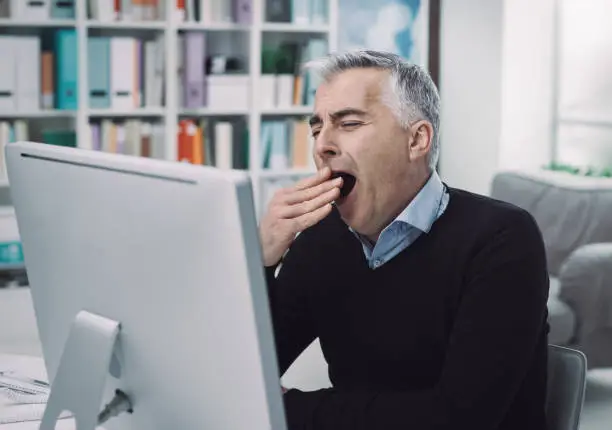 Photo of Tired bored office worker yawning