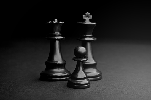 Chess. Black Pawn, King and Queen on black background.
