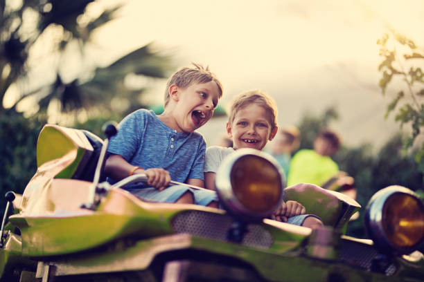 Kids having extreme fun in amusement park roller coaster Kids having fun in a small roller coaster in amusement park. Kids are laughing and shouting on a sunny summer day. amusement park photos stock pictures, royalty-free photos & images