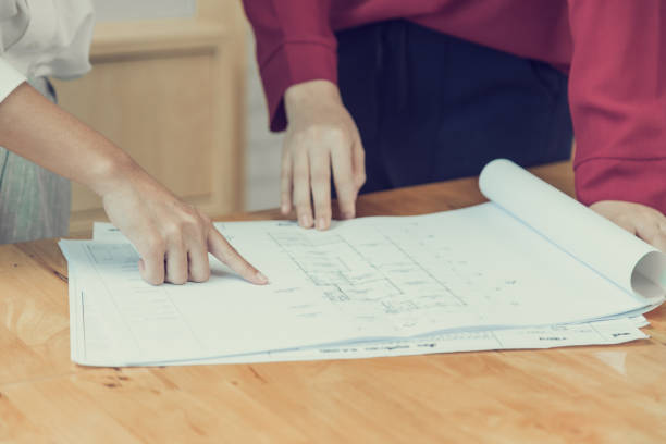 istock Female hands pointing at blueprint house plan drawing, good for building or architect concept 914934362
