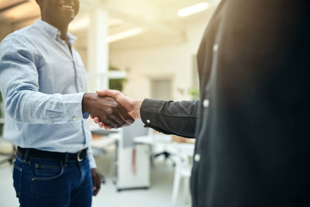 istock Two businessmen shaking hands together in a modern office 914934478