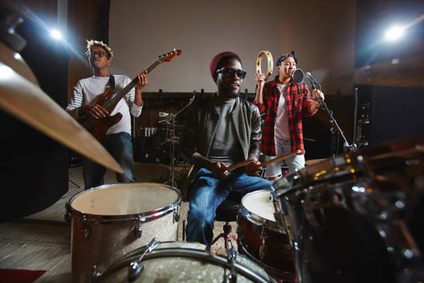 Young band Three young musicians playing musical instruments and performing songs in studio of records rock group photos stock pictures, royalty-free photos & images