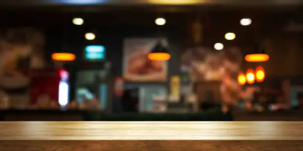 Empty wooden table top with blur coffee shop or restaurant interior background, Panoramic banner. Abstract background can be used product display.