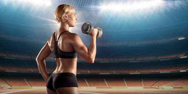 istock Fit woman on a stadium lifting weights 914940356