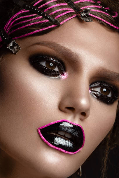 istock A beautiful girl with a black creative make-up and a pink thread on her lips. Beauty face. 914940982
