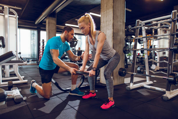 istock Young woman lifting weights with help of personal trainer 914949456