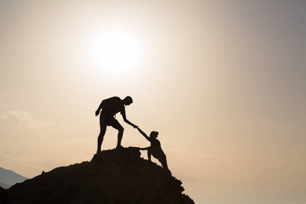 Teamwork couple helping hand trust in inspiring mountains Teamwork couple helping hand trust silhouette in inspiring mountains. Team of climbers assistance man and woman hiker, help each other on top of mountain, beautiful sunrise landscape in Crete Greece motivation photos stock pictures, royalty-free photos & images