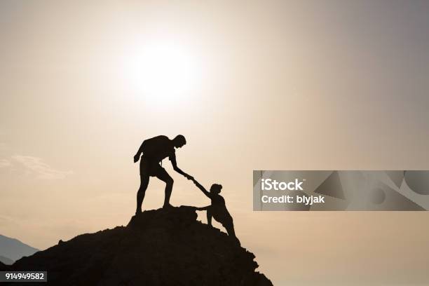 Teamwork Couple Helping Hand Trust In Inspiring Mountains Stock Photo - Download Image Now