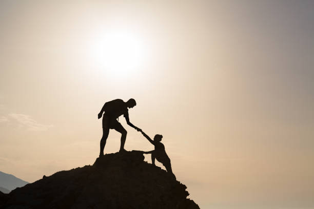 casal de trabalho em equipe, mão amiga confiar em inspiradoras montanhas - climbing clambering mountain silhouette - fotografias e filmes do acervo