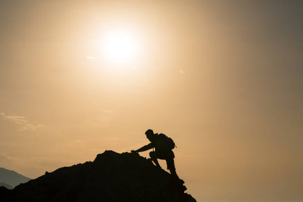 istock Climbing hiking silhouette in mountains over summer sunrise 914949640