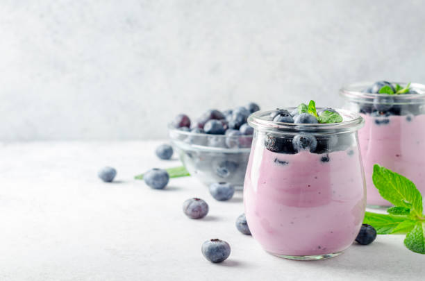 Blueberry yogurt with blueberries and mint Two glasses of blueberry yogurt with blueberries on a light gray stone background. Front view, copy space, horizontal image Cup of Blueberries stock pictures, royalty-free photos & images