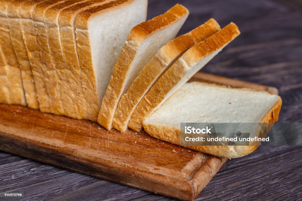 White bread sliced with slices on a wooden background close-up. Loaf of Bread Stock Photo
