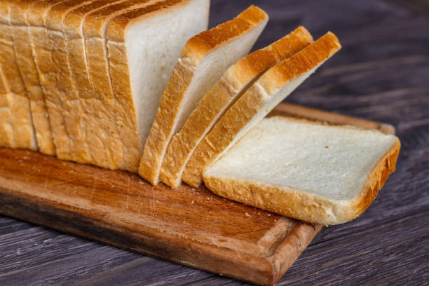 White bread sliced with slices on a wooden background close-up. White bread sliced with slices on a wooden background close-up. loaf of bread stock pictures, royalty-free photos & images