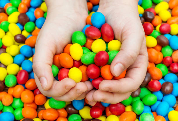 istock Child hands holds colorful round candies. 914977988