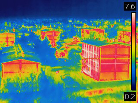 Image is taken with Flir T420 infra red camera. Image shows heat emission from heated buildings. Each color represents different temperatures, as is shown on spectrum scale on right side of image.