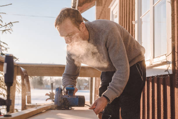 istock Man sawing wood for home improvement carpentry outdoors in cold winter 914980196