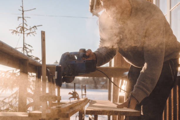 istock Man sawing wood for home improvement carpentry outdoors in cold winter 914980200