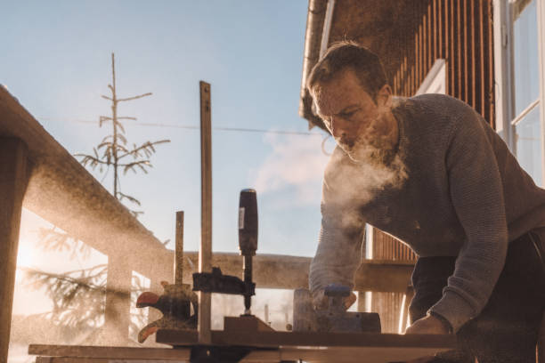 Man sawing wood for home improvement carpentry outdoors in cold winter