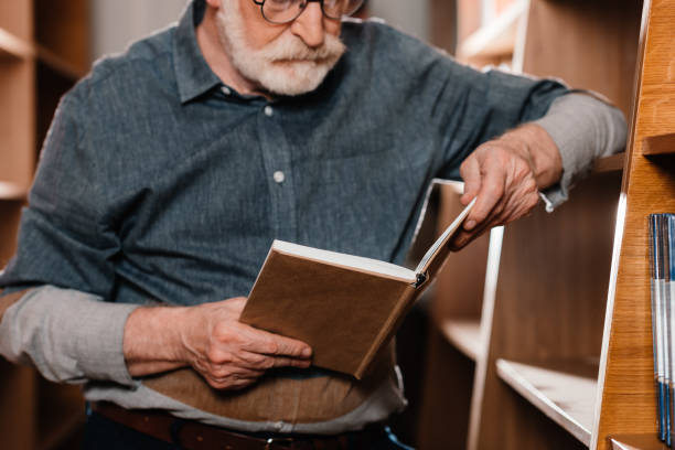 istock cropped image of grey hair librarian reading book 914983004
