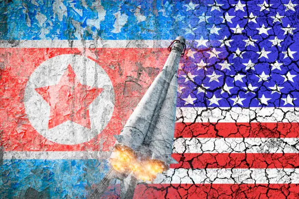 Photo of Confrontation between the USA and North Korea. Threat of nuclear strike. The flags of two countries painted on the concrete wall. Difficult relationship.