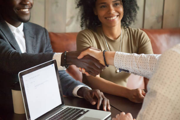 Happy african american couple making deal handshaking caucasian broker, closeup Happy young african american couple making deal handshaking caucasian insurance broker in cafe, black satisfied customer and Real Estate Agent or sales person shaking hands at meeting in office with laptop african american business couple stock pictures, royalty-free photos & images