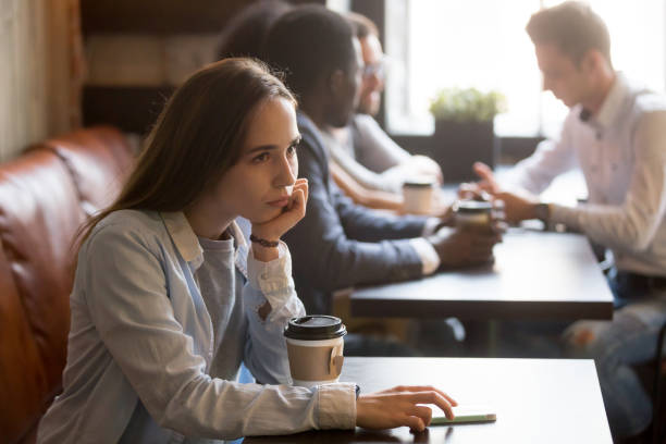 istock Pensive upset young girl sitting alone at table in cafe 914989836
