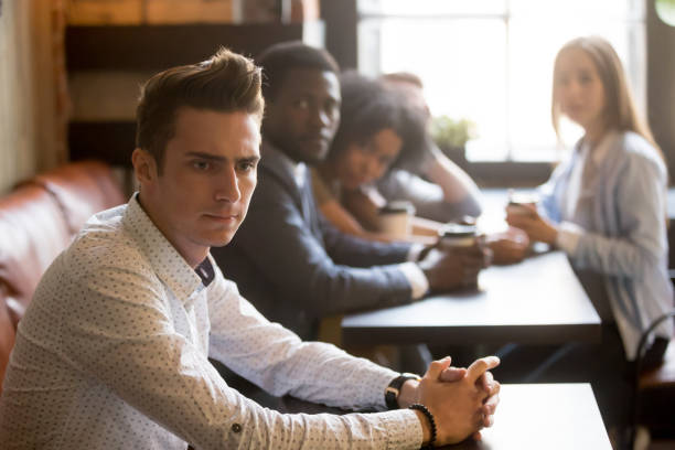 istock Diverse friends looking at frustrated man sitting alone in cafe 914989850
