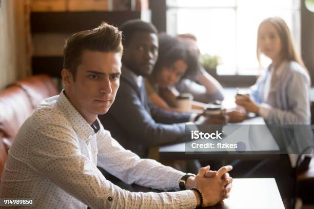 Diverse Friends Looking At Frustrated Man Sitting Alone In Cafe Stock Photo - Download Image Now