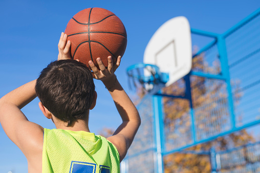 Adolescente, lanzar una pelota de baloncesto dentro del aro photo