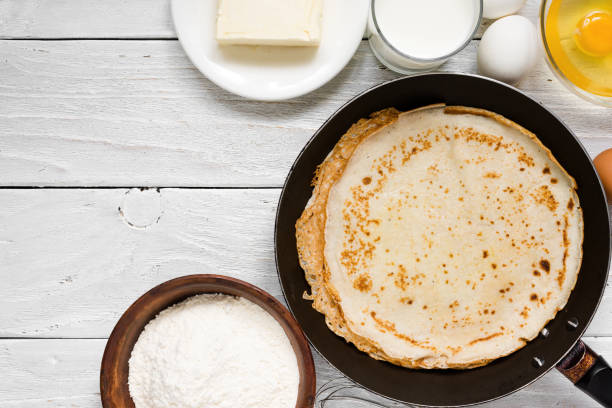 istock Stack of pancakes on frying pan with ingredients on white table 914989966