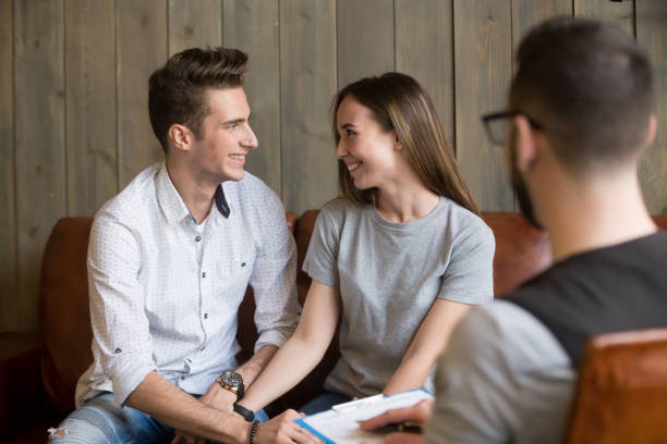 felice giovane coppia riconciliata che si fa il suo posto durante la sessione di terapia di consulenza - pleading men women reconciliation foto e immagini stock