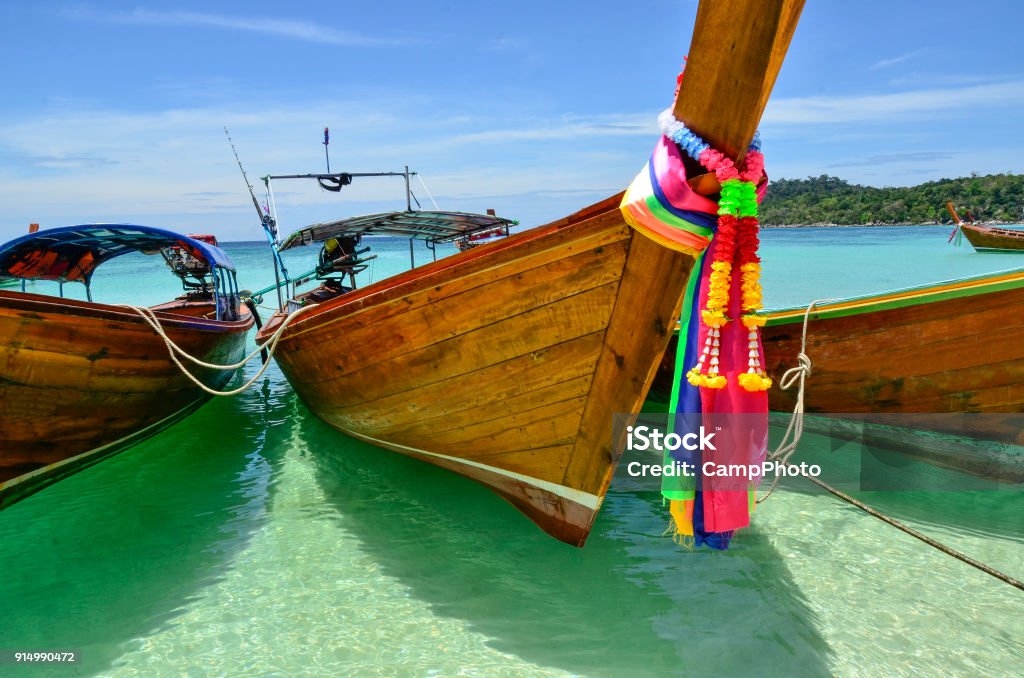 Tethered Longtails The long-tail boat is a type of watercraft native to Southeast Asia, which uses a common automotive engine. The ribbons tied to the bow of the boats are said to bring good luck. Ko Lipe, Thailand. Thailand Stock Photo