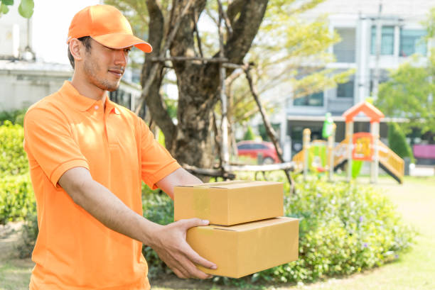 istock Delivery man in orange shirt is handing customer the package 914992666