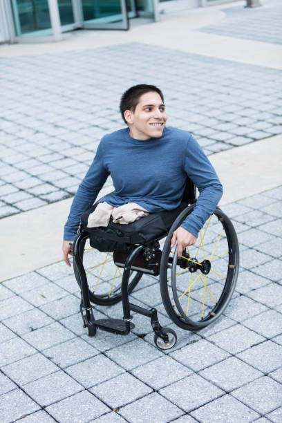 istock Young man in wheelchair on city sidewalk 914993962