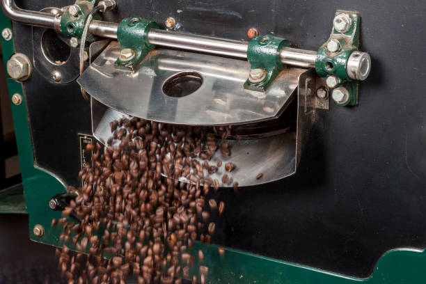 chicchi di caffè appena tostati che escono dal torrefattore - roasted machine bean mixing foto e immagini stock