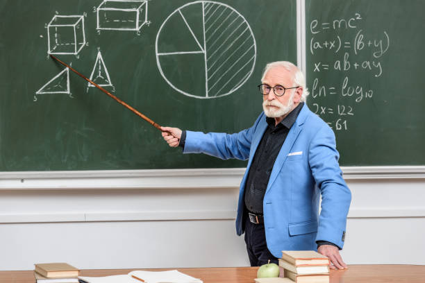istock grey hair professor pointing on something with wooden pointer 914998074