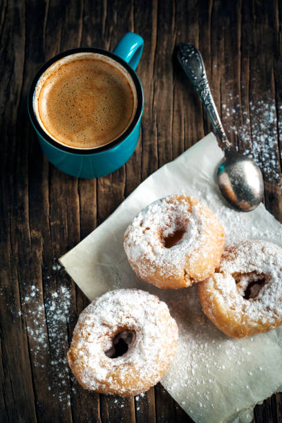 istock Donuts and cup of coffee on wooden background 914998422