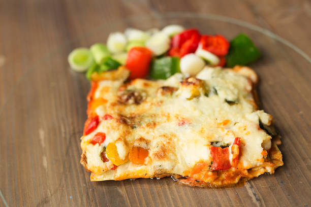 Italian food known as lasagna on a glass plate and a wooden background.