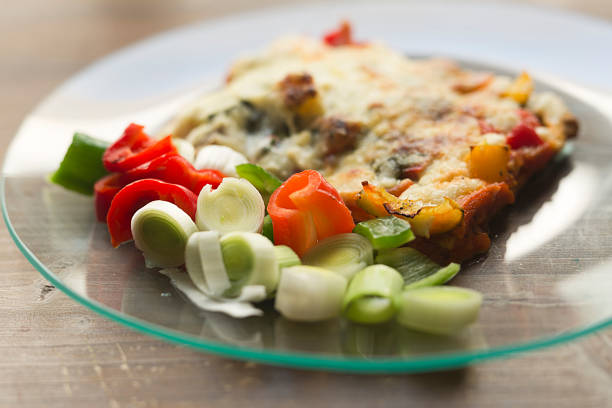 Vegetable lasagna in a glass dish on a wooden background.