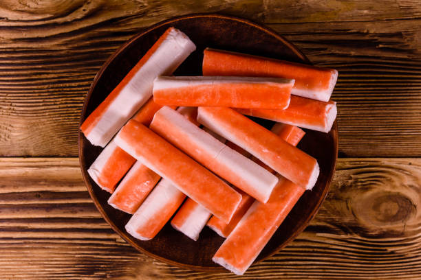 istock Ceramic plate with crab sticks on wooden table. Top view 915005780