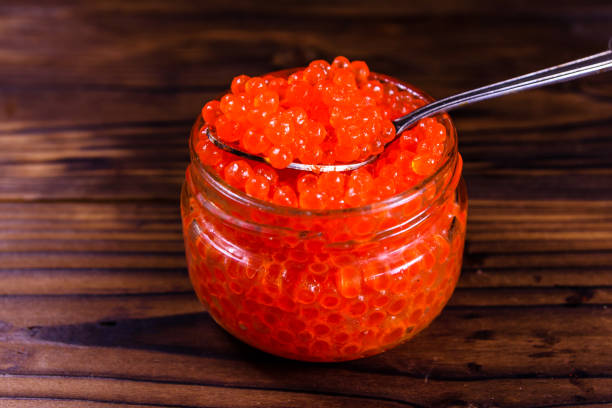 istock Red caviar in a spoon above the glass jar 915006018