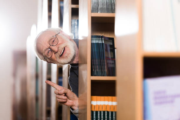 glücklich graue haare bibliothekar mit blick vom regal und idee geste zeigt - professor librarian university library stock-fotos und bilder