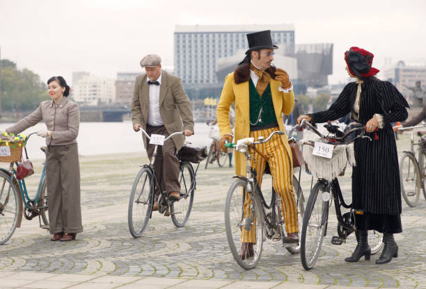 elegancka dama i dżentelmen z rowerami ubranymi w żółte i czarne ubrania, kapelusz cylindrowy i kapelusz z piór z aprox 1900 w bike in tweed - retro revival couple men elegance zdjęcia i obrazy z banku zdjęć