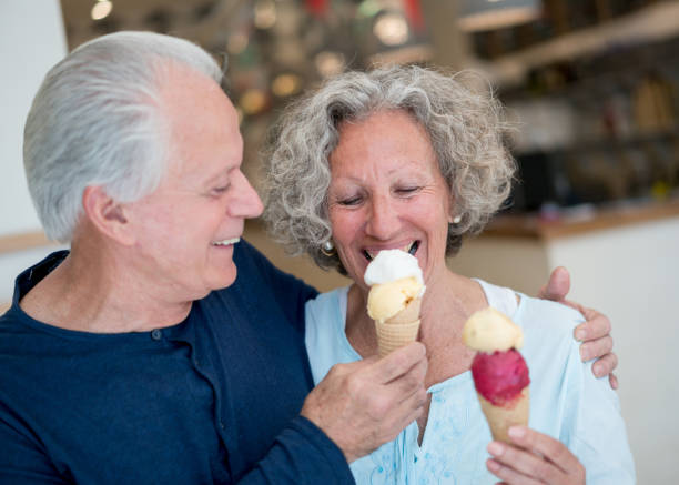 istock Senior man sharing his ice cream with his partner both looking very happy and laughing 915010544