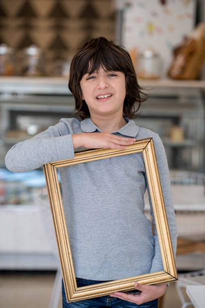 istock Cheerful boy holding an empty picture frame and looking at camera smiling 915010560