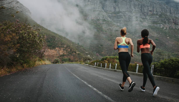 istock Two women athletes running on road 915018102