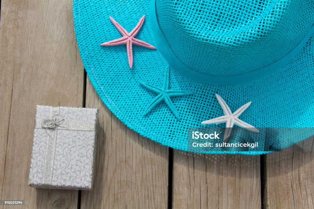Blue ladies hat and gift package on the table Hat, Straw Hat, Wood - Material, Clothing, Textile, gift, starfish Arts Culture and Entertainment Stock Photo
