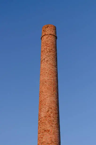 Photo of brick factory chimney against the blue sky