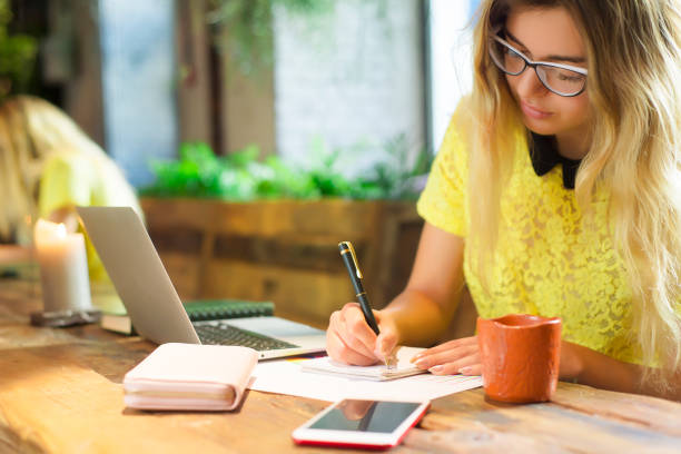 istock Young female student working on netbook, cute woman successful freelancer using laptop computer while sitting in coffee shop 915037470